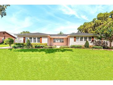 Charming single-story home with shutters, well-manicured lawn and mature landscaping in front yard at 2096 Lake Ariana Blvd, Auburndale, FL 33823
