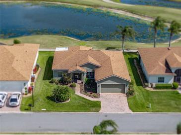 Aerial view of single-story home with beautiful landscaping, complemented by a serene pond and lush golf course backdrop at 4279 Ashton Club Dr, Lake Wales, FL 33859
