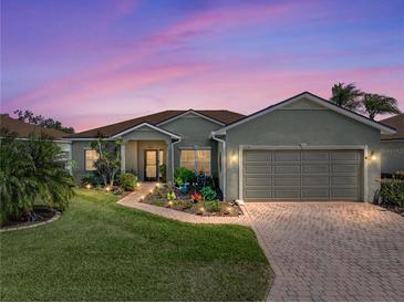 Charming single-story home with a well-maintained lawn, brick driveway, and inviting curb appeal at sunset at 4279 Ashton Club Dr, Lake Wales, FL 33859