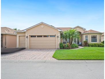 Charming single-story home with a well-manicured lawn, brick driveway, and attached two-car garage at 5200 Pebble Beach Blvd, Winter Haven, FL 33884