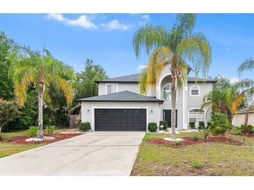 Two story home featuring a grey exterior, dark garage door, and landscaping with palm trees at 780 Gila Dr, Kissimmee, FL 34759