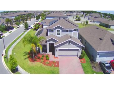 Charming two-story home with a well-manicured lawn, brick driveway, and attached two-car garage in a quiet community at 825 Grazie Loop, Davenport, FL 33837
