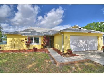 Charming single-story home with a well-manicured lawn, colorful plants, and a two-car garage at 103 Lake Thomas Dr, Winter Haven, FL 33880