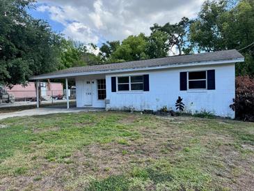 Single-story home featuring a carport, traditional windows, and a simple white facade, set amidst a green lawn at 128 11Th Wahneta W St, Winter Haven, FL 33880