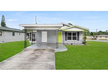 Charming single-story home with a grey exterior, well-maintained lawn, and a covered carport at 2020 Bassedena W Cir, Lakeland, FL 33805