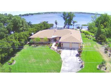 Aerial view of lakeside house with manicured lawn, mature trees, and a long driveway at 2611 State Road 557, Lake Alfred, FL 33850