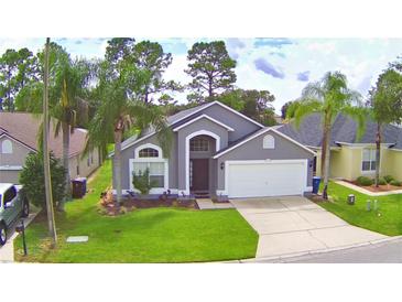 Charming single-story home featuring a well-manicured lawn, mature palm trees, and a two-car garage at 2721 Kokomo Loop, Haines City, FL 33844