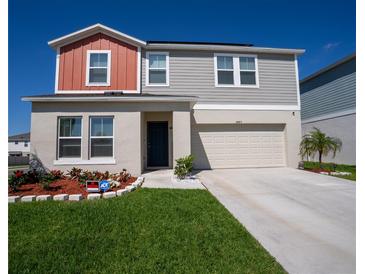 Charming two-story home with a well-manicured lawn, attached garage, and welcoming front entrance at 3440 Dahlia Dr, Haines City, FL 33844