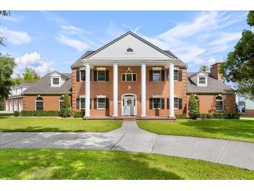 Stately brick home featuring large white columns, dormer windows, a manicured lawn and mature landscaping at 3826 Gaines Ct, Winter Haven, FL 33884