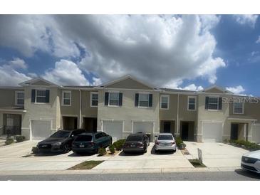Well-maintained townhomes with a row of garages under a partly cloudy sky at 386 Feltrim Reserve Blvd # 386, Davenport, FL 33837
