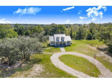 Sprawling property features a charming home with a metal roof, circular driveway, and lush surroundings at 6344 Old Lake Wilson Rd, Davenport, FL 33896