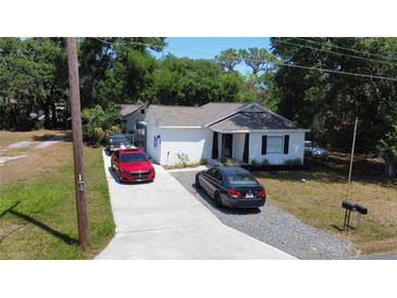 Charming single-story home with white siding, dark shutters and trim, and a concrete driveway with multiple cars parked at 730 Druid St, Lakeland, FL 33805