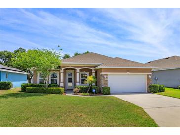 Charming single-story home featuring a manicured lawn, stone accents, and a two-car garage at 135 Eloise Oaks Dr, Winter Haven, FL 33884