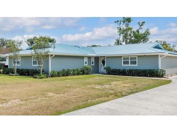 Charming single story home featuring a metal roof, mature landscaping, and a well-manicured lawn at 317 Oak Trl, Lakeland, FL 33813