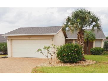 Charming single-story home featuring a lush palm tree, manicured landscaping, and a two-car garage at 4007 Cypress Lndg S, Winter Haven, FL 33884