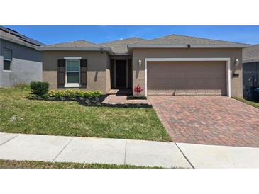 Charming single-story home featuring a brick driveway, manicured lawn and neutral color palette at 625 Disa Dr, Davenport, FL 33837