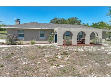 Charming single-story home featuring a covered patio with arched openings and a well-maintained front yard at 9019 Oakwood Dr, Lake Wales, FL 33898