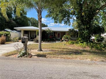 Charming single-story home with mature landscaping and a metal roof on a sunny day at 124 Palm Pl, Haines City, FL 33844