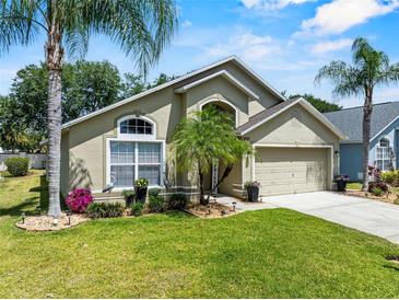 Charming single Gathering home featuring lush landscaping, mature palm trees, and a two-car garage at 1357 Rebecca Dr, Haines City, FL 33844
