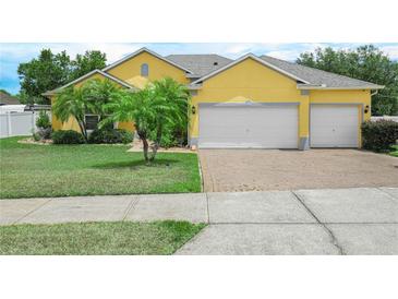 Charming yellow house with a well-manicured lawn, mature palm trees, and a two-car garage at 147 Brookshire Dr, Lake Wales, FL 33898