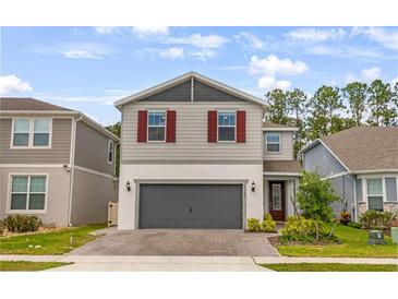 Charming two-story home with gray siding, brick driveway, red shutters, and well-maintained landscaping at 2356 Palm Park Loop, Clermont, FL 34714