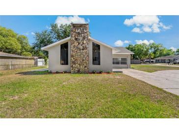 Charming single-story home with a stone chimney and well-maintained front yard on a beautiful day at 3022 Lantana Rd, Auburndale, FL 33823