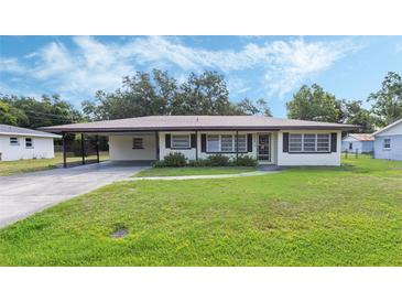 Charming single-story home featuring a lush lawn and an inviting carport at 5829 Lake Breeze Ave, Lakeland, FL 33809