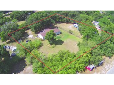 Expansive aerial view of a wooded lot with mature trees and single-Gathering home and outlined with a red boundary line at 1294 1/2 38Th Nw St, Winter Haven, FL 33881