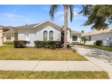 Charming one-story home with well-manicured lawn, tidy hedges and mature palm tree in lush Florida landscape at 135 Minniehaha Cir, Haines City, FL 33844