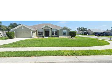 Well-manicured front yard of a single-story home featuring a lush green lawn, complemented by a paved driveway and sidewalk at 1400 Eagle Crest Blvd, Winter Haven, FL 33881