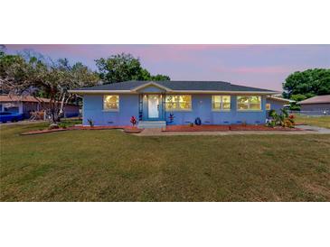Charming blue home boasts a well-manicured lawn and inviting entryway with a sidewalk and a landscaped garden at 1515 W Lake Cannon Nw Dr, Winter Haven, FL 33881