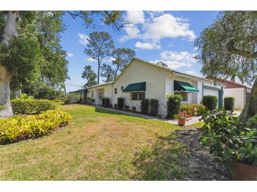Charming single-story home with a well-manicured lawn, green awnings, and mature trees at 441 San Jose Dr, Winter Haven, FL 33884