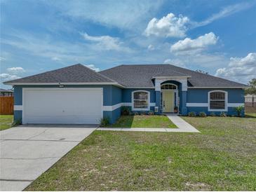 Charming blue single-story home featuring a well-manicured lawn and a bright yellow front door at 541 Hatchwood Dr, Haines City, FL 33844