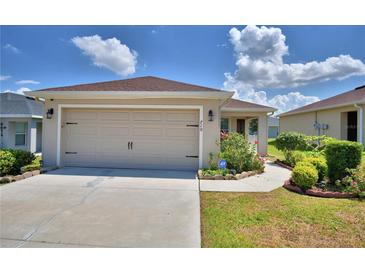 This home features an attached two-car garage with manicured flower beds, lawn and landscape along the driveway at 710 Persian Dr, Haines City, FL 33844