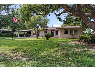 Charming single-story home with a well-manicured lawn, mature trees, and a covered parking area at 105 Leslie Ave, Winter Haven, FL 33880