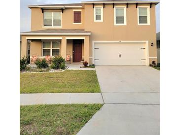 Charming two-story home featuring a well-maintained lawn, covered front porch, and attached two-car garage at 1378 Fox Squirrel Dr, Davenport, FL 33897
