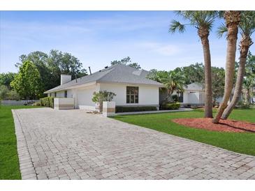 Charming one-story home with a paved driveway, lush lawn, and mature palm trees at 2987 Plantation Rd, Winter Haven, FL 33884