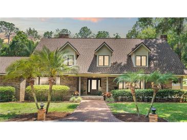 Charming brick home featuring a manicured lawn, complemented by lush palm trees and a welcoming brick pathway at 418 North Rd, Lakeland, FL 33809