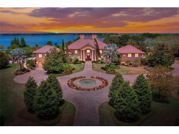 Stunning waterfront home boasts mature landscaping and a circular driveway with center water feature at 501 Adams Barn Rd, Auburndale, FL 33823