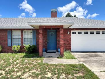 Charming brick home with a blue front door, shutters, and a well-manicured lawn under a sunny sky at 504 W 7Th St, Frostproof, FL 33843