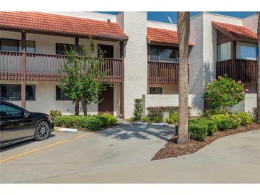 Condo exterior featuring a red tile roof, covered balcony, and well-maintained landscaping with ample parking at 5102 Village Ct # E-2, Lake Wales, FL 33898