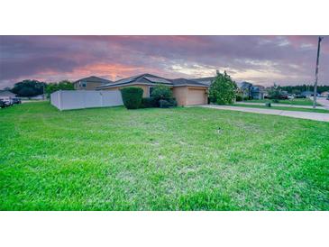 Well-maintained single-story home featuring a spacious green lawn and a white picket fence at 713 Overlook Grove Dr, Winter Haven, FL 33884