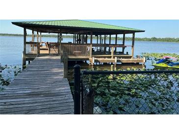 A spacious dock with a green roof and Jet Ski is an amazing feature for lake access and recreation at 9402 Cat Track Trl, Lake Wales, FL 33898