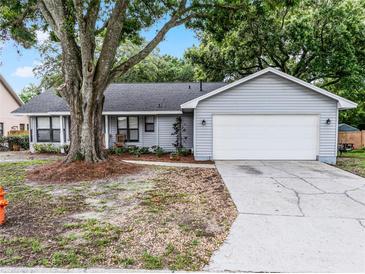 Charming single-story home with a large tree in the front yard and a two-car garage at 125 Homewood Dr, Winter Haven, FL 33880