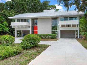 Stunning contemporary home featuring a white metal roof, tall windows, red door, and covered parking at 1540 N Lake Mirror Nw Dr, Winter Haven, FL 33881