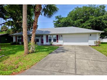 Charming single-story home with a well-manicured lawn, a two-car garage, and mature landscaping at 2909 Pine Tree Dr, Edgewater, FL 32141