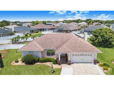 Well-maintained single-Gathering home featuring lush landscaping, a two-car garage, and a charming, light-colored exterior at 413 Ruby Lake Pl, Winter Haven, FL 33884