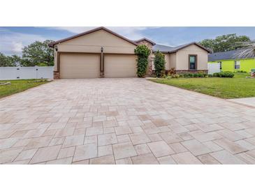 Inviting home featuring a two-car garage, neutral paint, stone accents, and a long, patterned paver driveway at 607 S 16Th St, Haines City, FL 33844