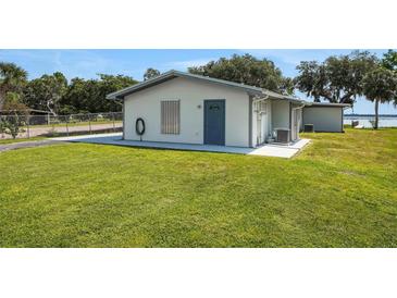 Inviting single story home with blue door, grassy lawn and waterfront views at 8314 W Lake Marion Rd, Haines City, FL 33844