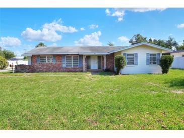 Charming single-story home with a brick facade and well-maintained front lawn and a lush green lawn at 961 Piedmont Se Dr, Winter Haven, FL 33880
